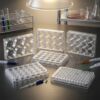 Transparent sterile cell culture plates with various well configurations including 6 well, 12 well, 24 well and 96 well formats in a laboratory environment.