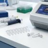 PCR tube strip and loose tubes beside pipettes and a thermal cycler.